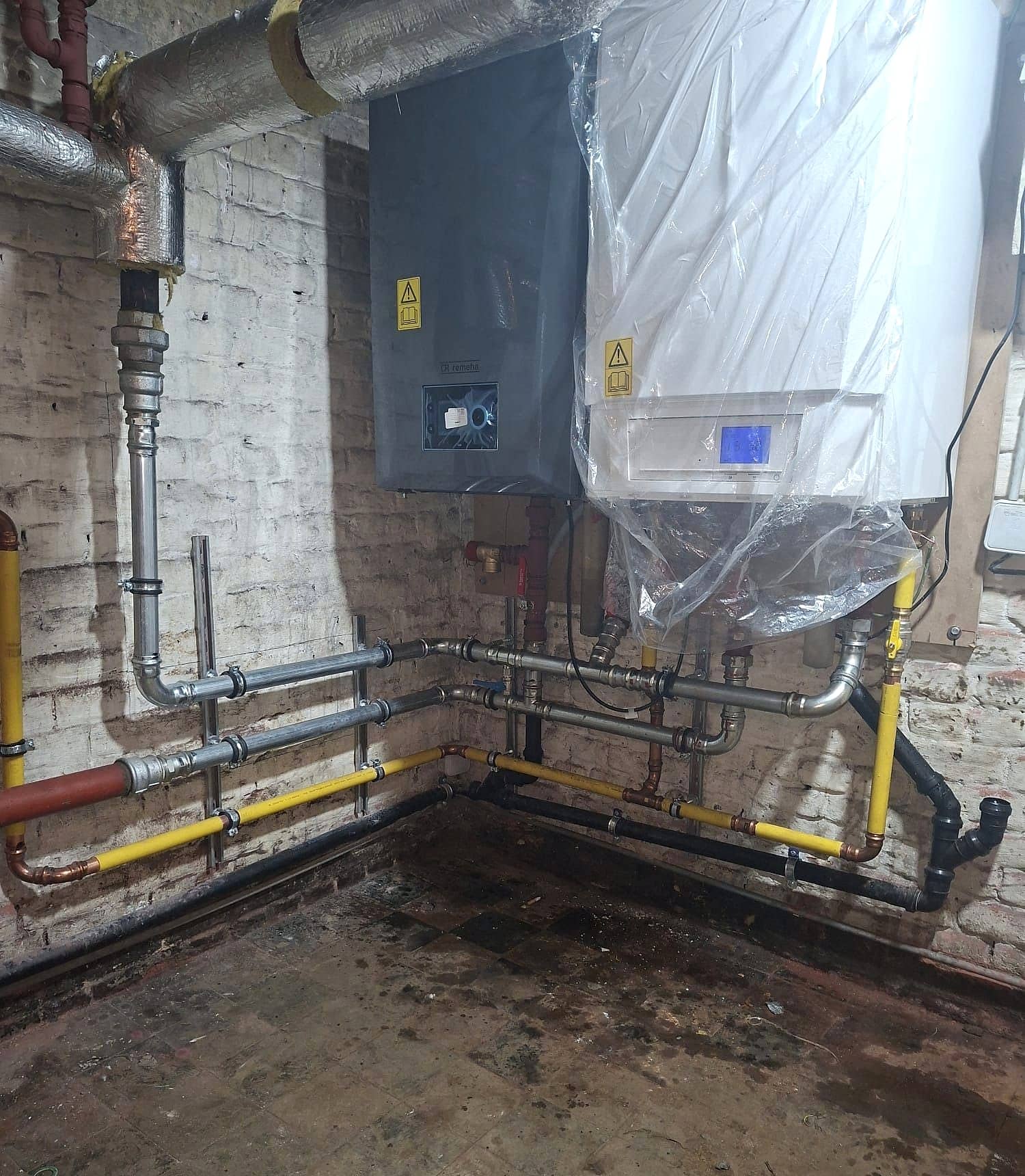Chaudière murale Remeha anthracite et appareil voisin raccordés en acier serti, conduite de gaz jaune et évacuation noire