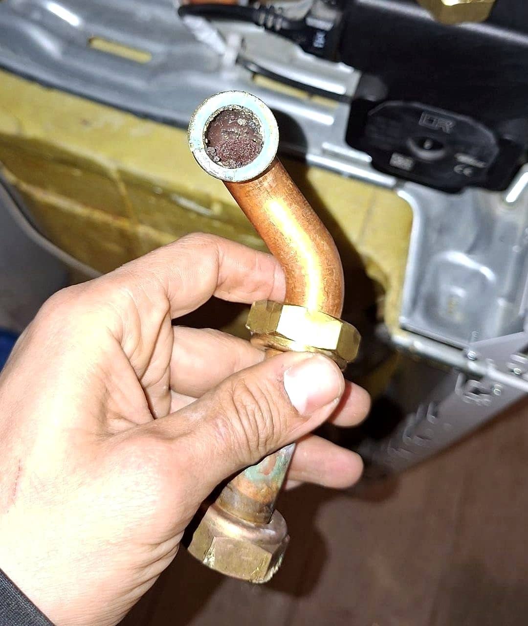 Tuyau en cuivre démonté d’une chaudière, presque entièrement bouché par des boues et du tartre