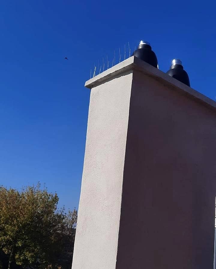 Souche de cheminée enduite en toiture avec deux terminaux d’évacuation des fumées, sous un ciel bleu
